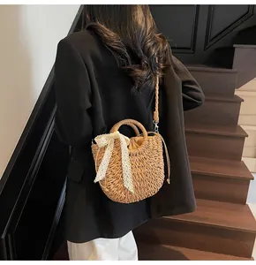 Détail du sac demi-lune en paille avec nœud en dentelle et bandoulière sur un mannequin