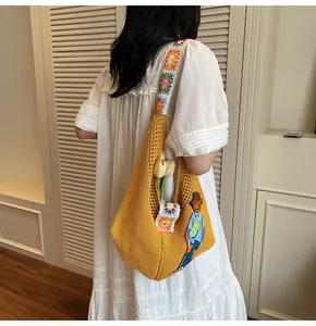 Detail of a yellow crochet shoulder bag with floral knit strap and cartoon patch