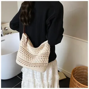 Detail of hollow-out floral weave on a cream crochet shoulder bag with leather strap