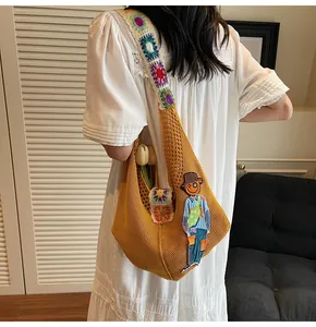 Detail of yellow knit tote bag featuring crochet floral straps and scarecrow embroidery