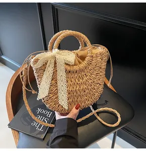 Détail d'un sac en paille tissé avec grand nœud en dentelle blanche et chaîne perlée