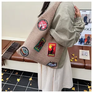 Détail du sac hobo en maille kaki avec écussons brodés colorés de mothman et bigfoot