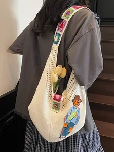 White hand-knitted hobo bag with colorful floral strap and guitar character patch