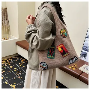 Détail du grand sac à bandoulière en tricot avec des écussons brodés de cryptozoologie