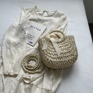 Vue à plat du sac à main en paille crème avec nœud en dentelle et bandoulière assortie