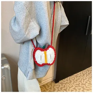 Detailed back view of a child wearing the red knitted apple cross-body bag over a grey hoodie