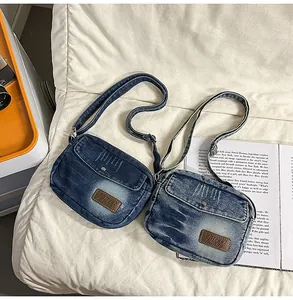 Détail du sac bandoulière en denim délavé vintage avec boucle métal et étiquette en cuir