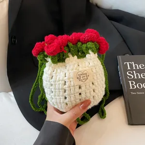 Détail du sac seau rose crocheté main avec fleurs rouges et cordon de serrage feuille verte