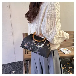 Detail van vintage Chinese handtas met bamboe handvat en parelketting schouderriem