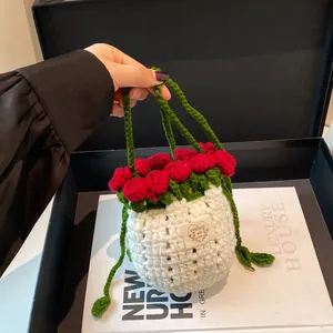 Détail d'un sac seau fait main avec fleurs au crochet rouges et étiquette