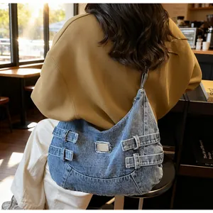 Dettaglio di una grande borsa hobo in denim indossata da una modella in un caffè