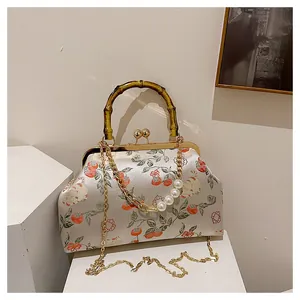 Detail van vintage geborduurde tas met bamboe handvat en parelketting decor