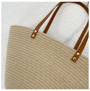 Detail of woven straw tote bag texture with brown leather strap and gold metal rivets