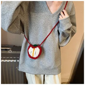 Detail of handmade crochet apple-shaped mini crossbody bag with red and white knit texture