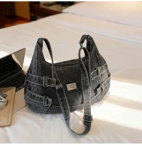 Dettaglio della borsa a tracolla in denim nero lavato con fibbie metalliche regolabili