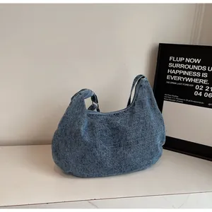 Dettaglio di una borsa a tracolla in denim blu capiente con struttura morbida e cerniera