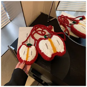 Detail of handmade crochet apple-shaped crossbody bags in two sizes on wooden table