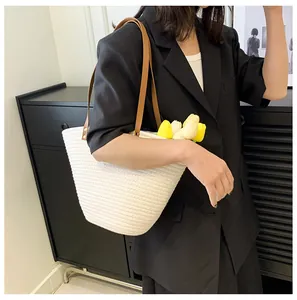 Detail of woven straw tote bag with brown leather straps and fresh flowers inside
