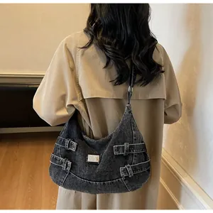 Dettaglio della borsa a tracolla in denim vintage con fibbia metallica su trench beige