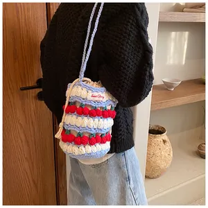 Detail of crochet bucket bag with red cherry accents and a Sweet Cherry label