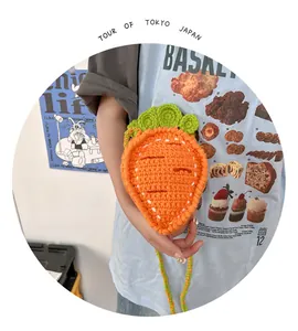 Detail of handmade crochet carrot bag featuring orange yarn texture and green leaf design