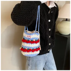 Detail view of handmade crochet bucket bag with cherry patterns and drawstring lining