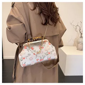Detail van vintage geborduurde tas met bamboe handvat en elegante parelketting riem
