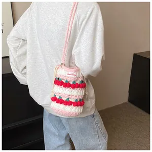 Detailed back view of a handmade crochet cherry bucket bag worn on the shoulder