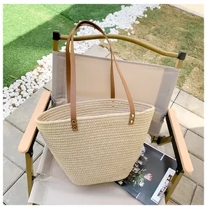 Detail of woven straw tote bag with brown leather straps on a casual outdoor chair