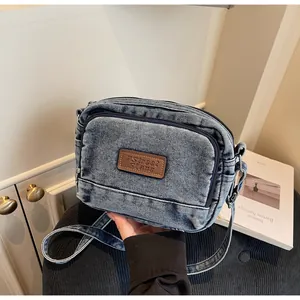 Dettaglio borsa a tracolla in denim retrò con logo in pelle e doppie cerniere lampo