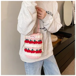 Detail of handmade crochet cherry bucket bag showing pink woven texture and sweet label