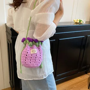Détail d'un sac seau au crochet avec fleurs 3D violettes et bandoulière tissée