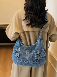 Borsa a spalla vintage in denim blu con fibbie metalliche indossata da modella in trench