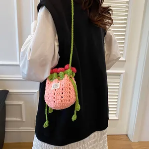 Détail du sac seau fraise tricoté rose montrant l'étiquette faite main et la bandoulière tissée