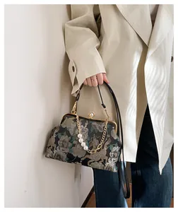 Detail van vintage jacquard handtas met bloemenborduurwerk en elegante parelsluiting