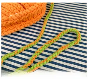 Close-up of hand-crocheted carrot bag showing orange yarn texture and two-tone strap