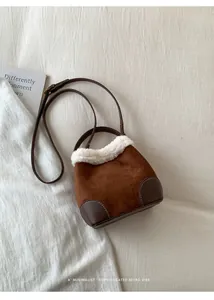 Détail du sac seau en daim marron avec bordure en fausse fourrure blanche et sangle