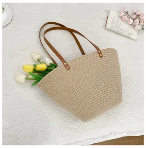 Detail of hand-woven straw tote with brown leather handles and vibrant tulip flowers