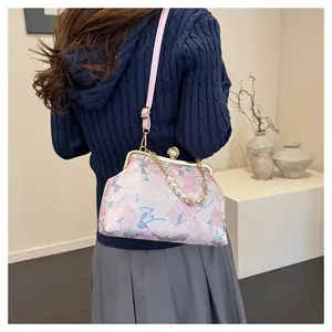 Detail van bloemenborduurwerk op roze crossbodytas met bamboe handvat en parelketting