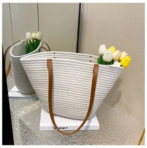 Detail of woven tote bag with brown leather handles and reinforced metal rivets
