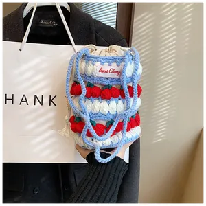Detail of handmade crochet bucket bag with cherry embroidery and drawstring closure