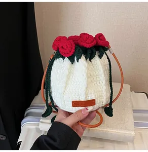 Close-up of handmade white crochet bucket bag featuring red woven roses and leather tag