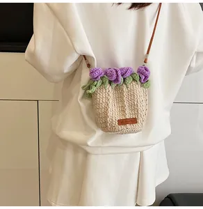 Detail of hand-knitted cream bucket bag with purple rose and brown crossbody strap