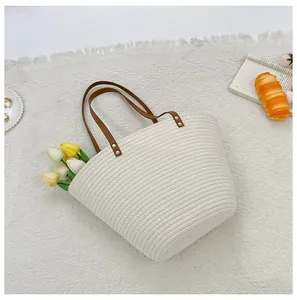 Detail of hand-woven beige tote bag with premium brown leather handles and gold rivets
