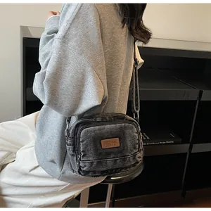 Dettaglio della borsa a tracolla in denim nero vintage con scomparti multipli a zip
