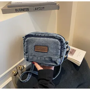 Dettaglio borsa a tracolla in denim blu con toppa in pelle su un elegante mobile bianco