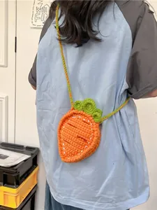 Handmade crochet carrot crossbody bag for kids featuring green leaves and braided strap