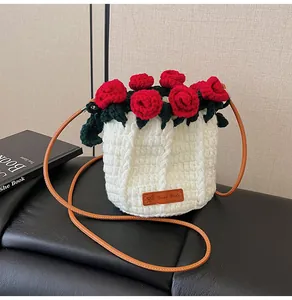 Detail of hand-crocheted bucket bag with red roses, green leaves and a leather strap