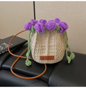 Detail of hand-knitted beige bucket bag with purple flowers and brown leather tag