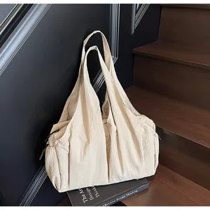 Detail of beige pleated shoulder bag with side pocket and smooth zipper closure